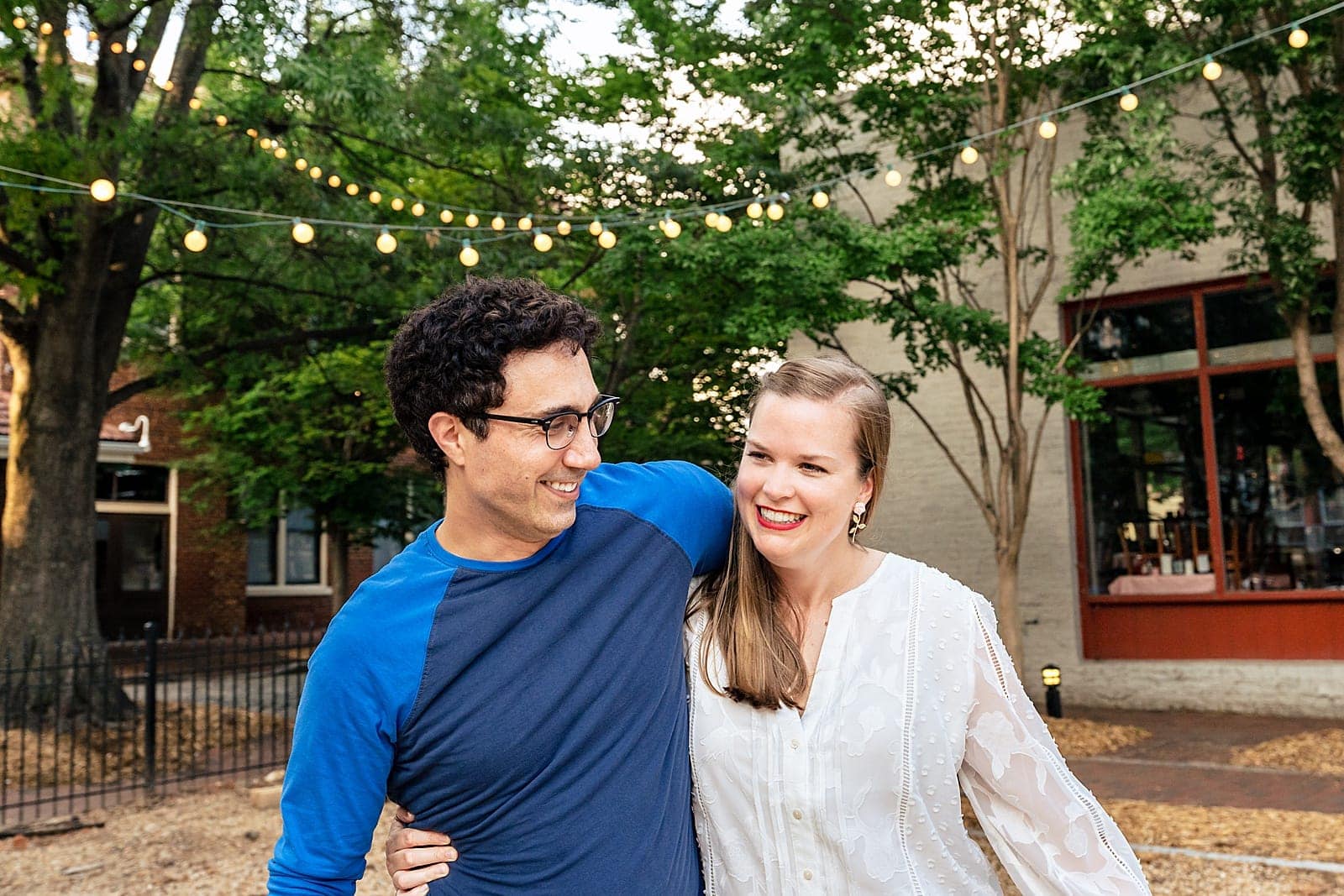 City Market Engagement Photos - couple laughs and walks through City Market in downtown Raleigh