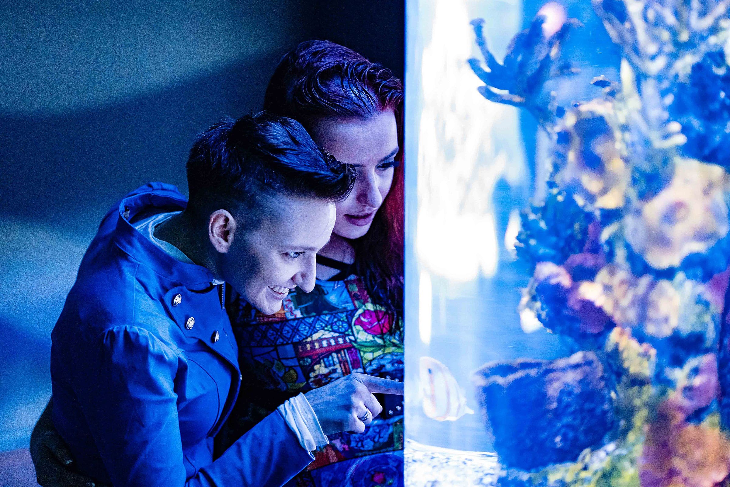 Engaged couple looks at aquarium tank | Disney engagement, disney engagement photos, Disney portraits, epcot engagement photos, kivusandcamera.com, magic kingdom engagement photos, same-sex engagement photos, Walt Disney World engagement photos