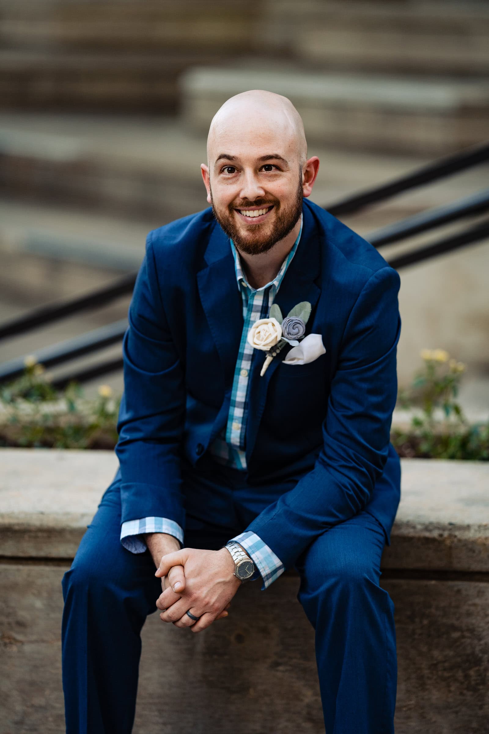 Man in a blue suit poses in front of a staircase for Durham Anniversary portraits