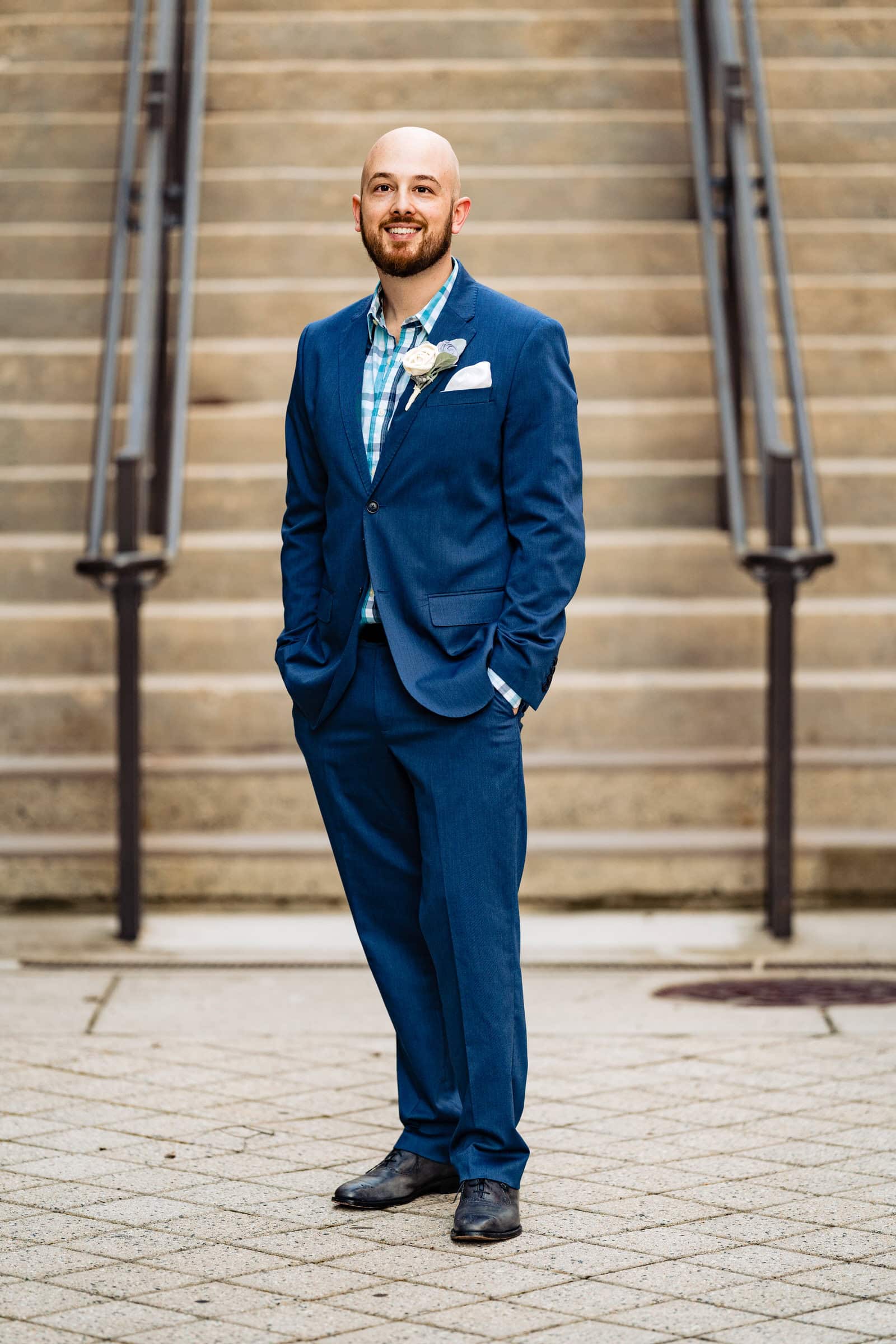 Man in a blue suit poses in front of a staircase for Durham Anniversary portraits