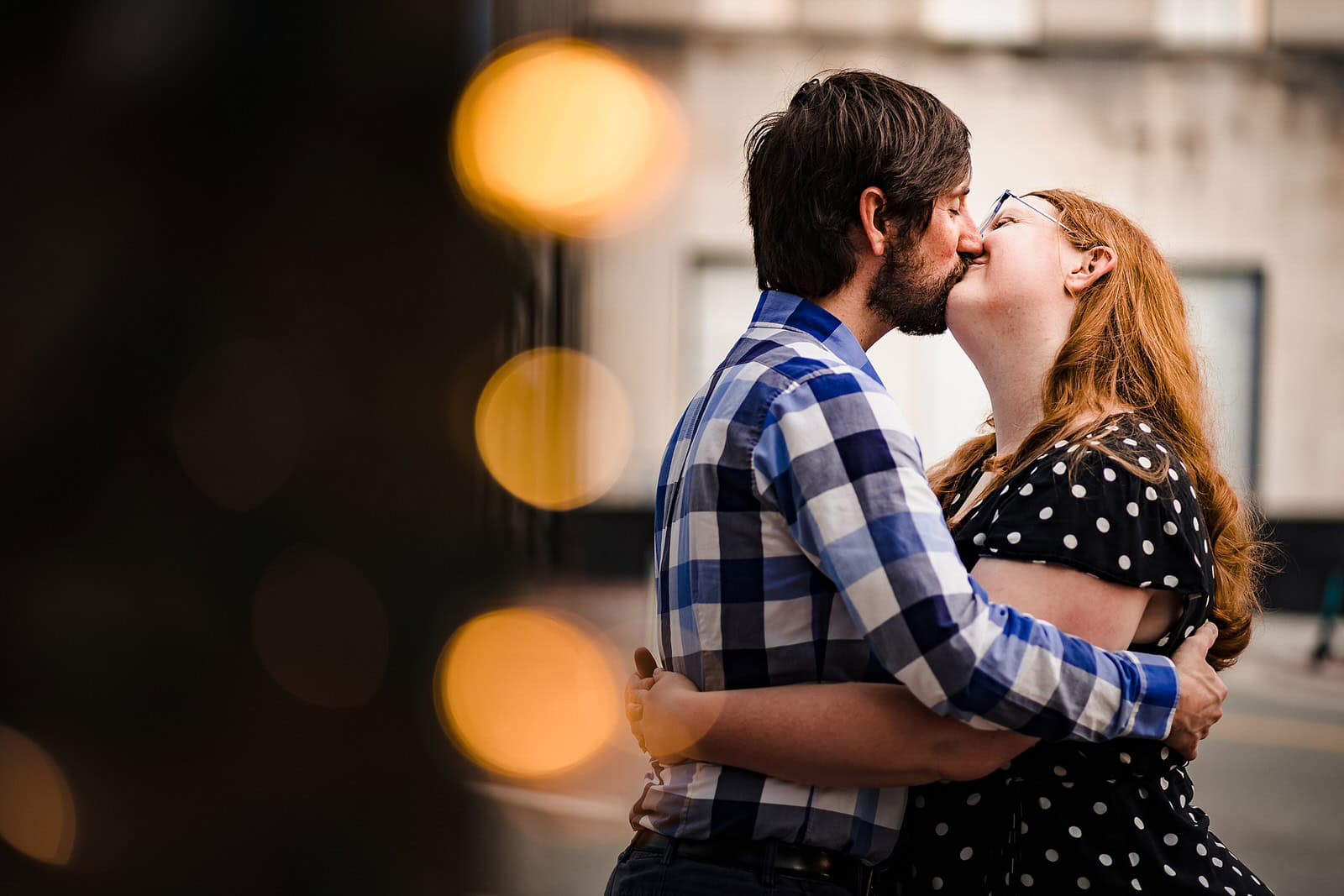An engaged couple embrace and kiss