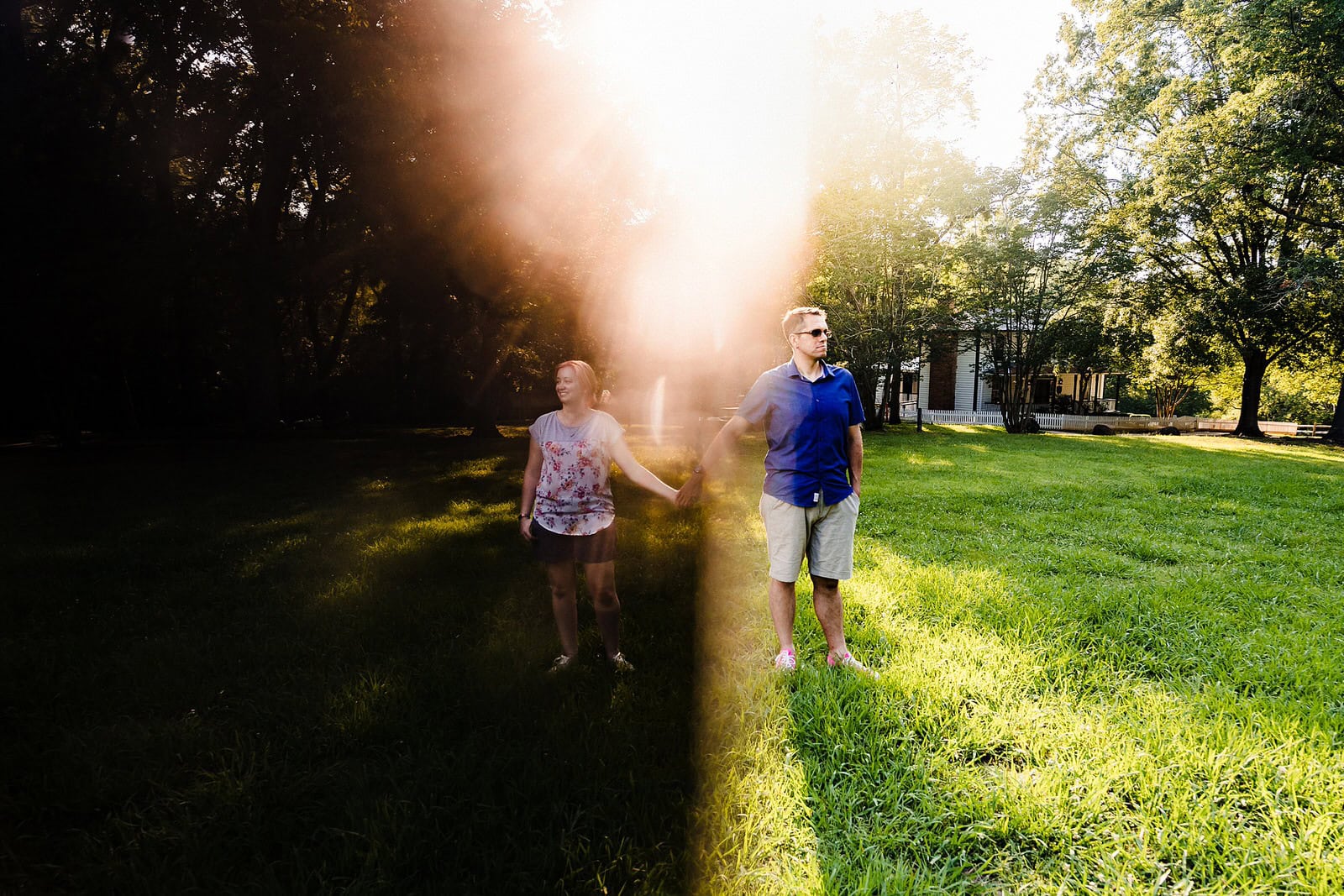 A couple holds hands. The man stands in light, the woman stands in darkness. 