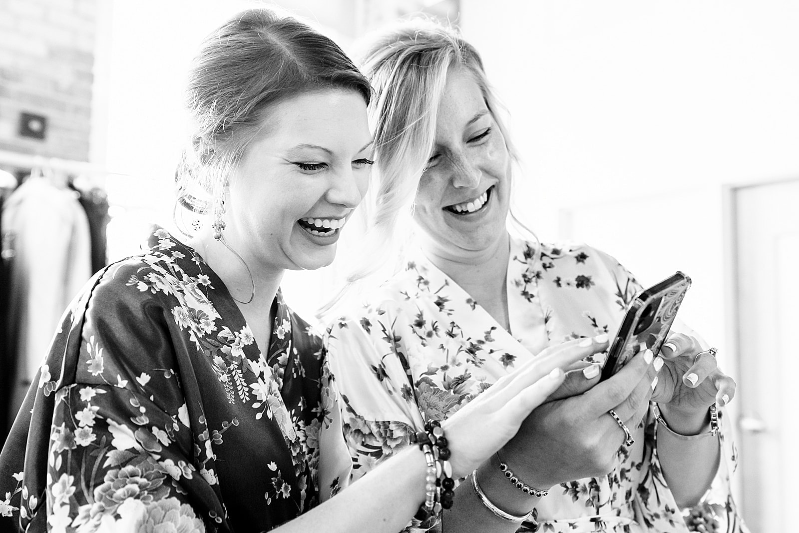 bride laughs with her maid of honor at her wedding at the Cotton Room in Durham