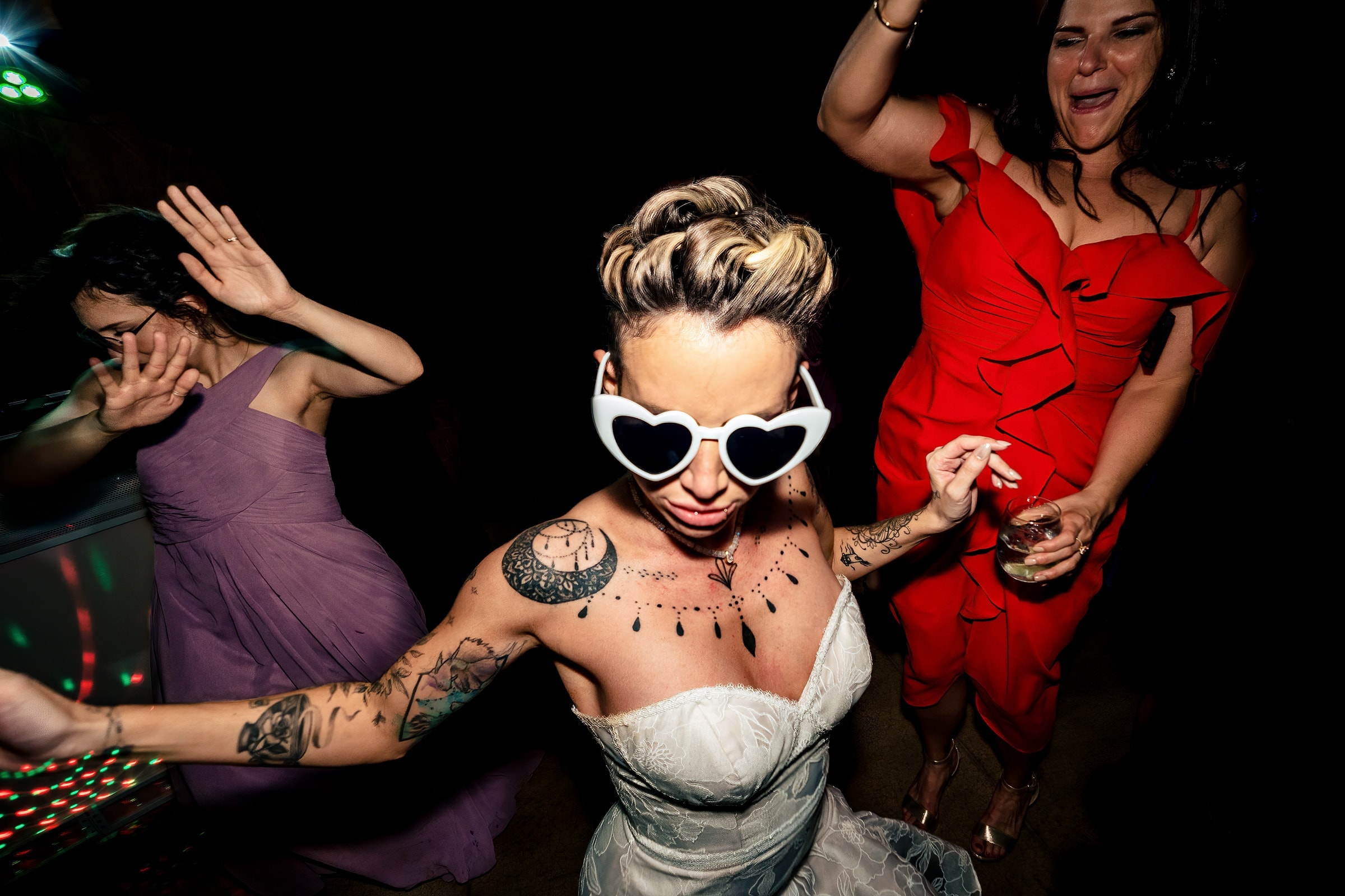 Bride in white, heart-shaped sunglasses dances at her wedding reception. Part of the Kivus & Camera Raleigh wedding vendor guide