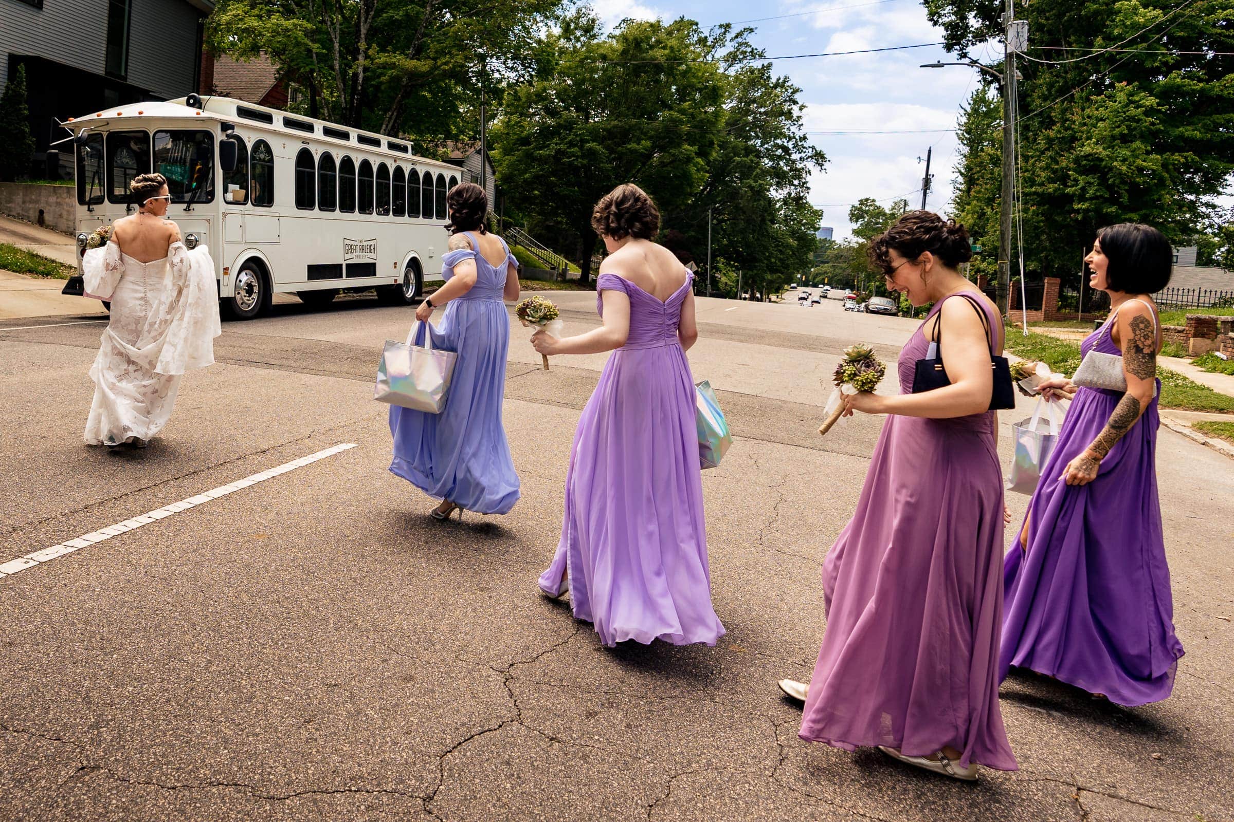 bride and bridesmaids cross the road to get on the Great Raleigh Trolley | Kivus & Camera