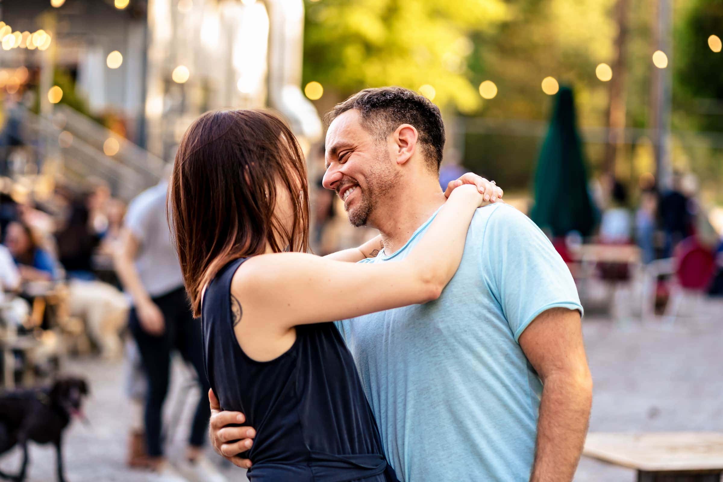 man and woman smile at one another with their arms around eachother