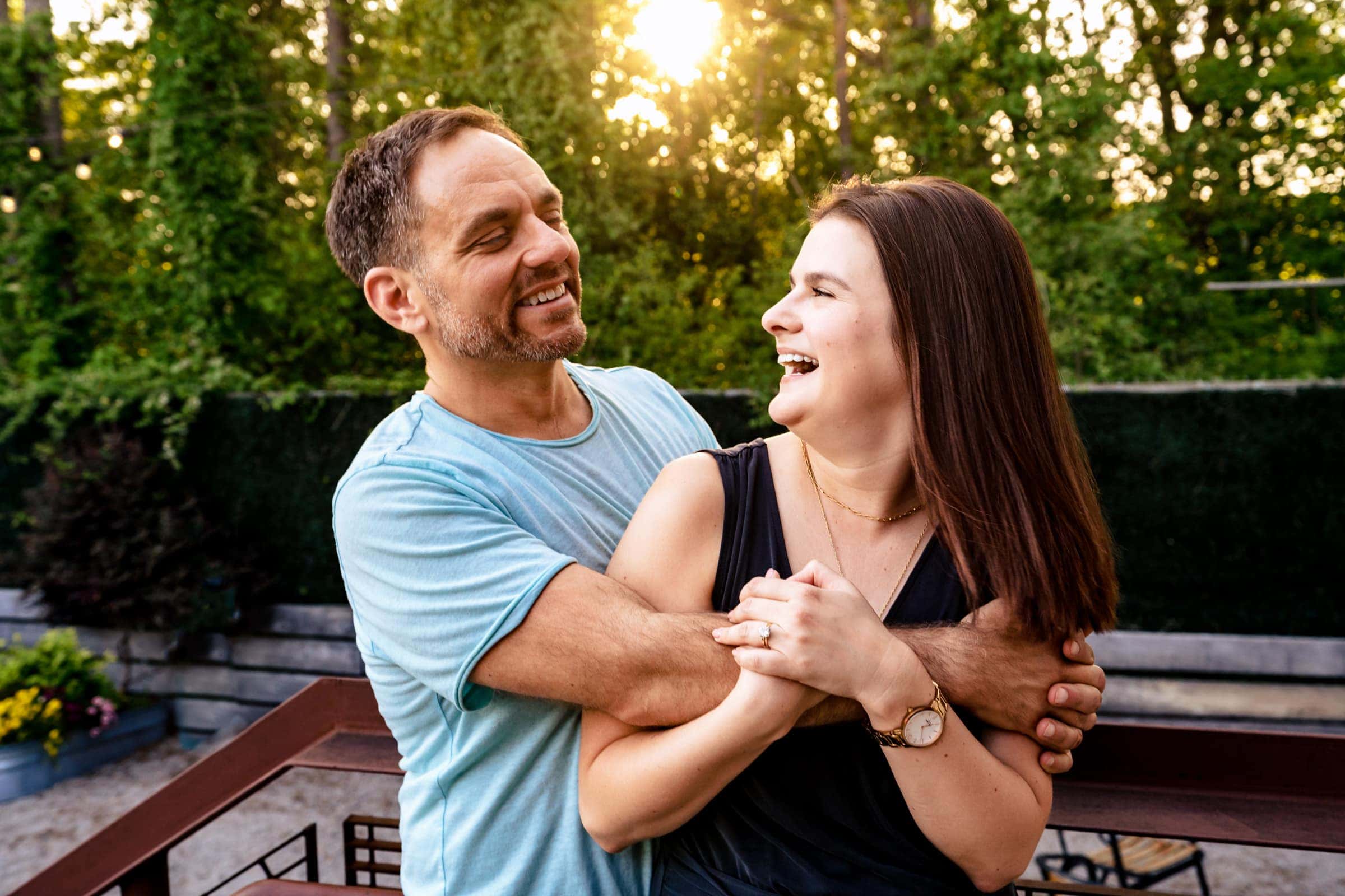 man and woman smile at one another with their arms around eachother