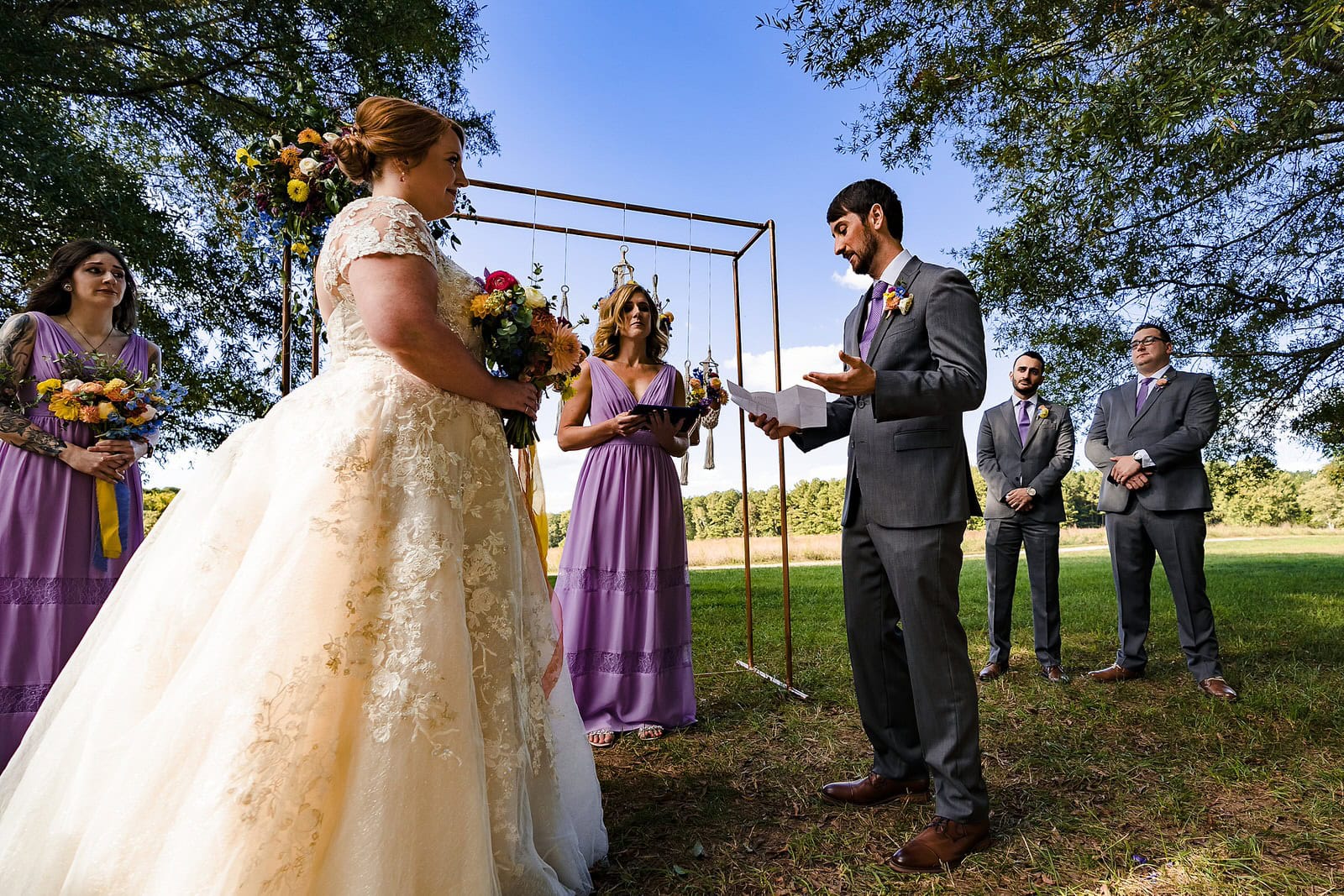 Groom reads his personal vows during outdoor wedding ceremony