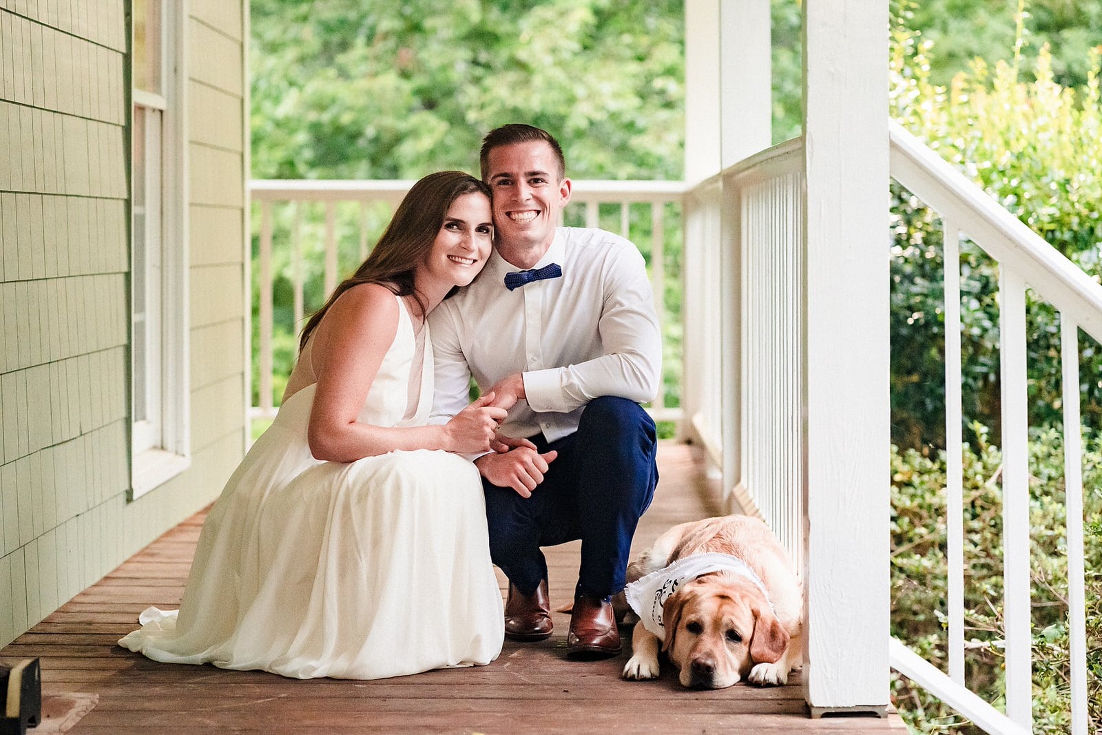 bride and groom pose with their dog who has a bandanna that says dog of honor