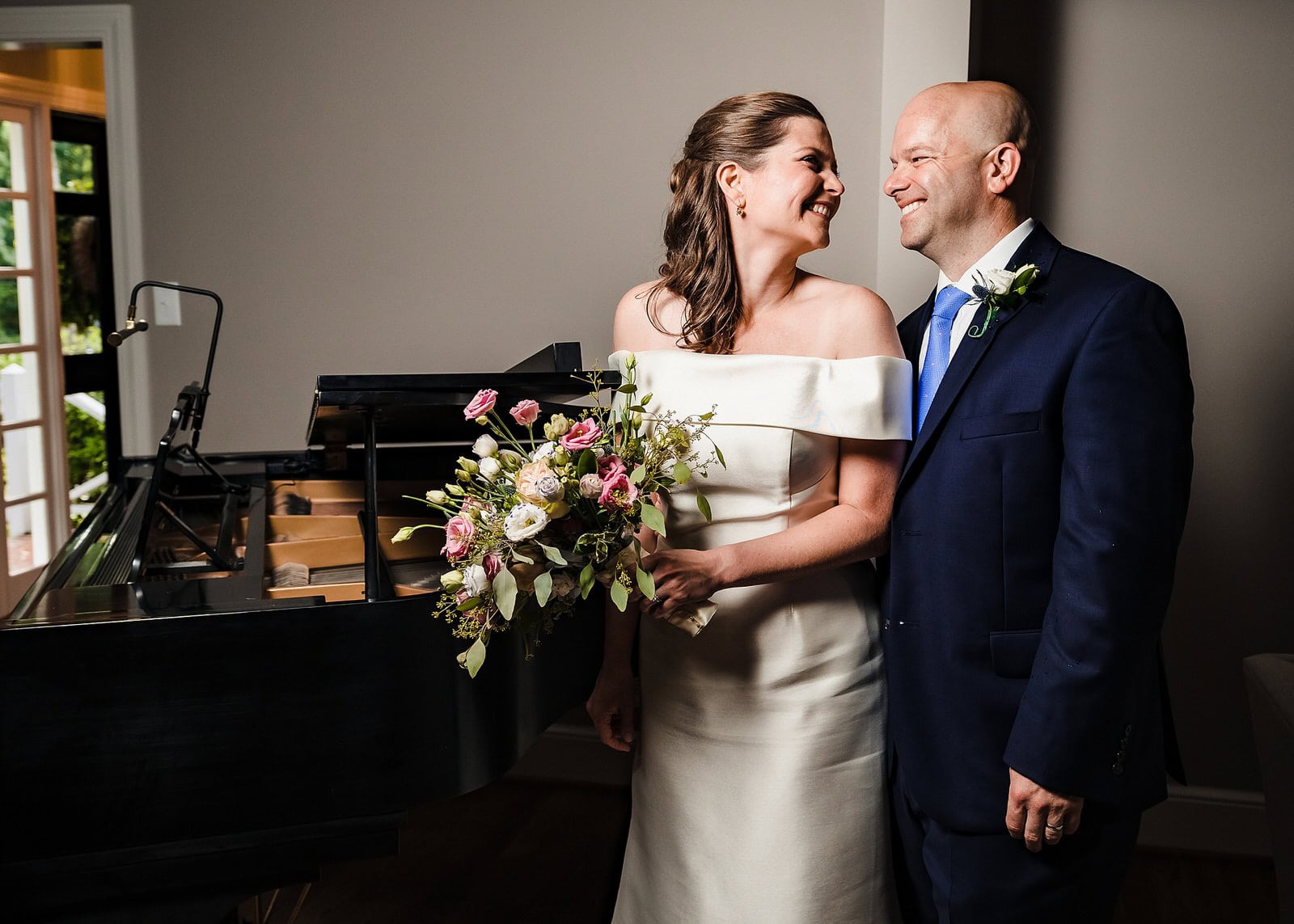 bride and groom smile and laugh in their living room