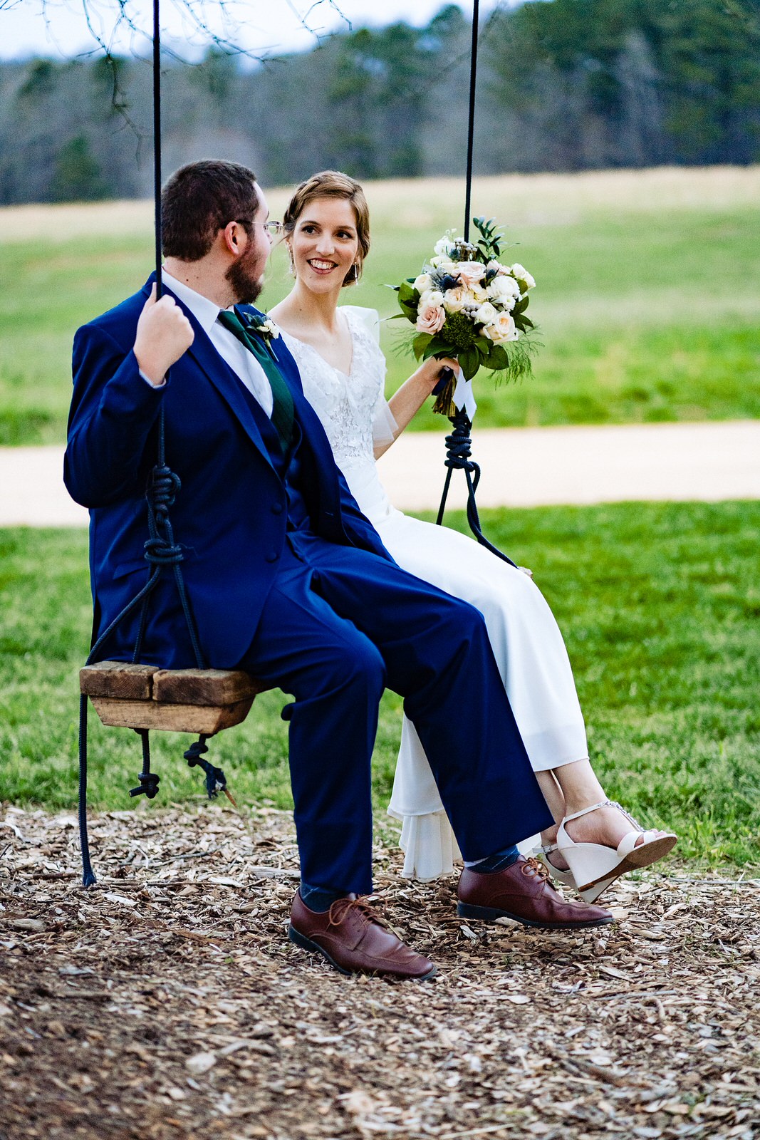 Bride and groom on a tree swing on their wedding day at The Meadows Raleigh