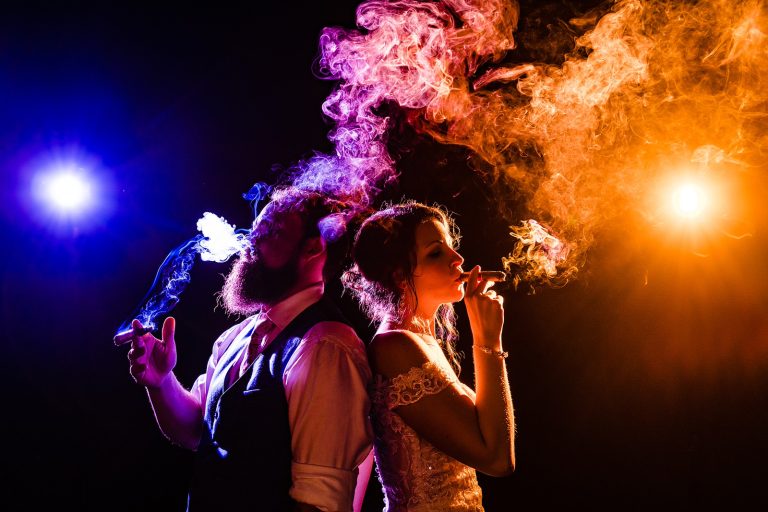 Bride and groom smoke cigars; dramatic wedding photography