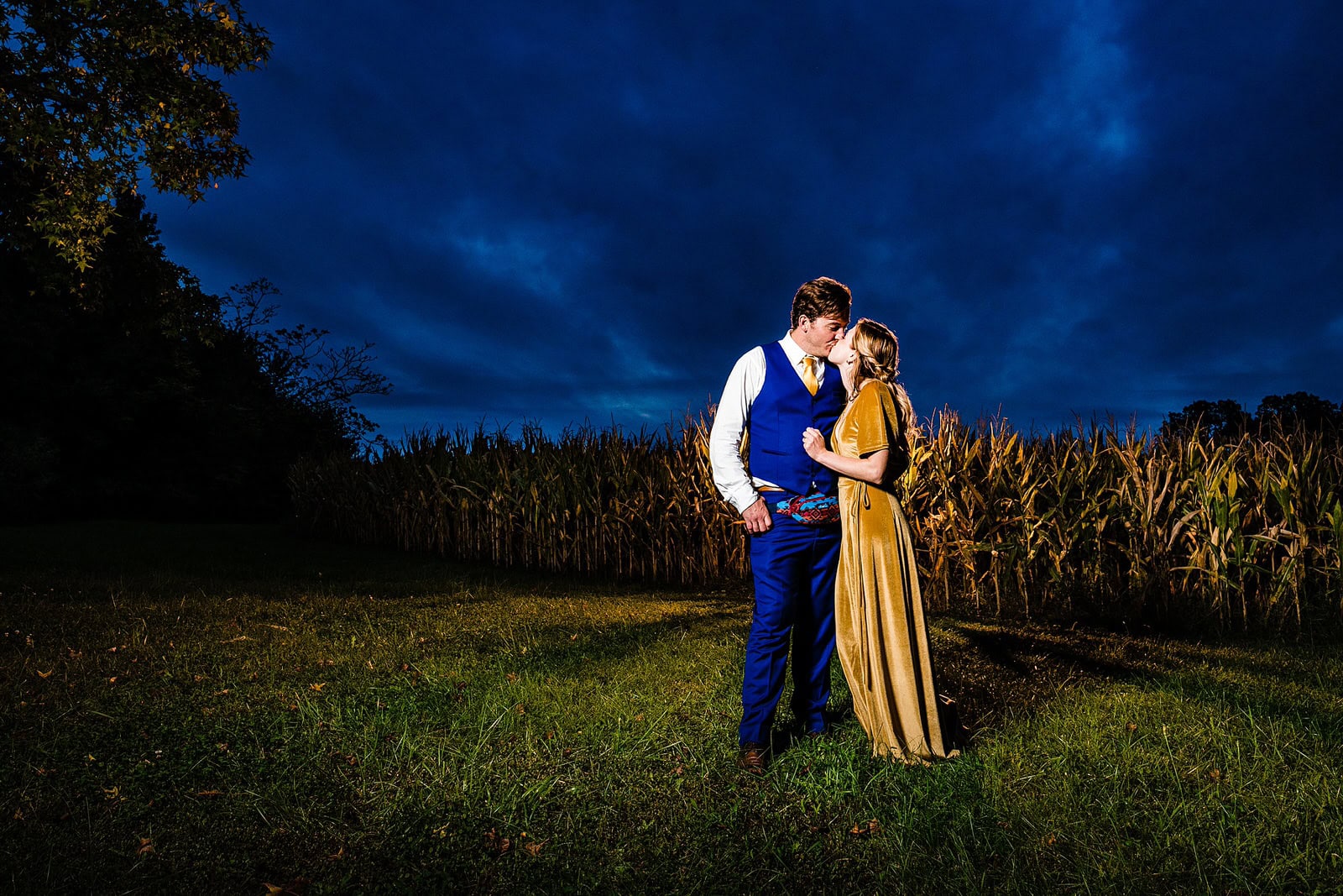 Couple poses for a dramatic portrait at blue hour in front of a corn field