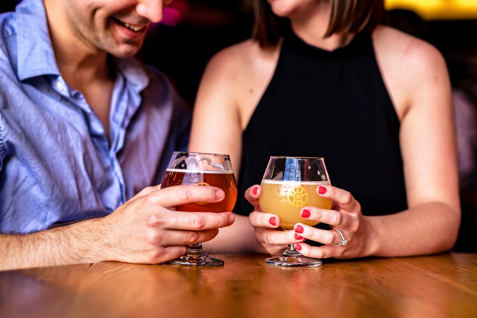 man and a woman holding beers at Crank Arm - one of the best Raleigh breweries