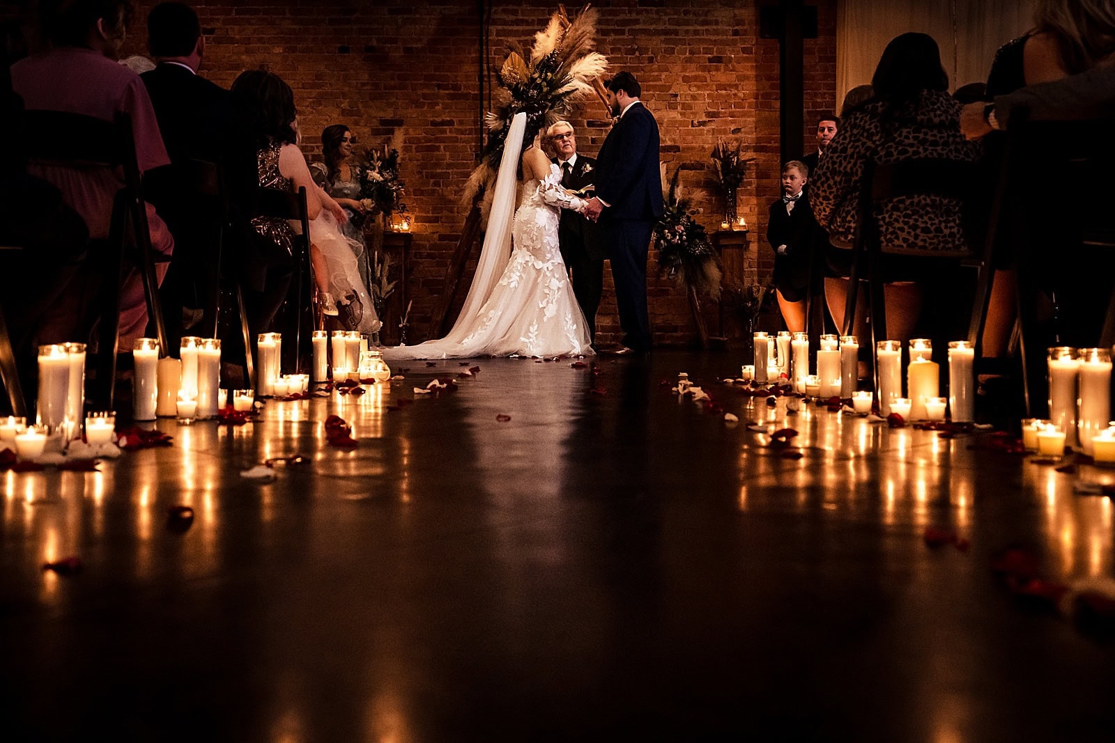 candle-lit wedding ceremony at Brick & Mortar events with backdrop made by friends and family of the couple