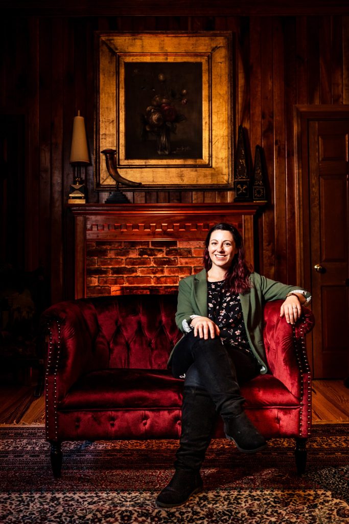 Stephanie from Beauty & The Budget sits on a red velvet couch at The Matthews House. Beauty & The Budget Events is one of the best Raleigh Wedding Planners. | photo by Kivus & Camera