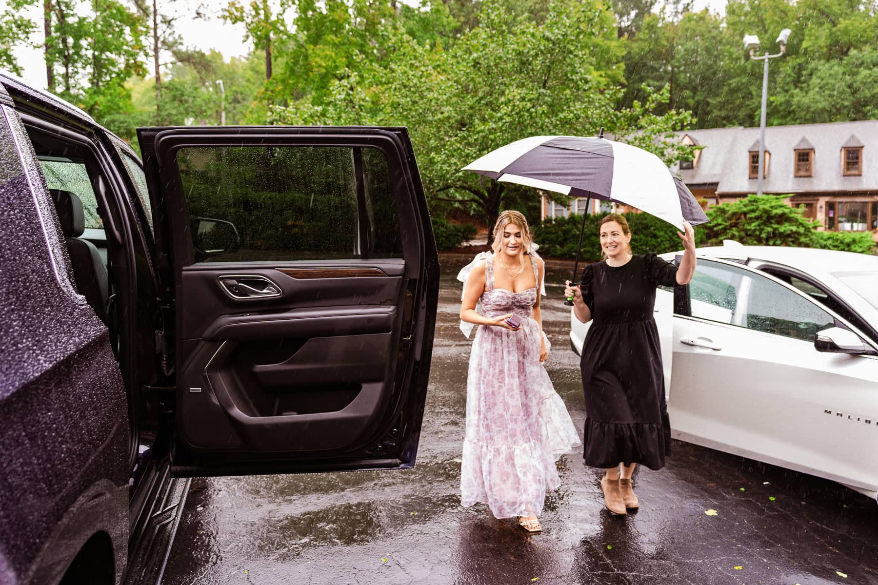 wedding planner Bethany from Harmony Weddings carried an umbrella over a bridesmaid as she walks to the car. Part of the Raleigh wedding vendor guide from Kivus & Camera