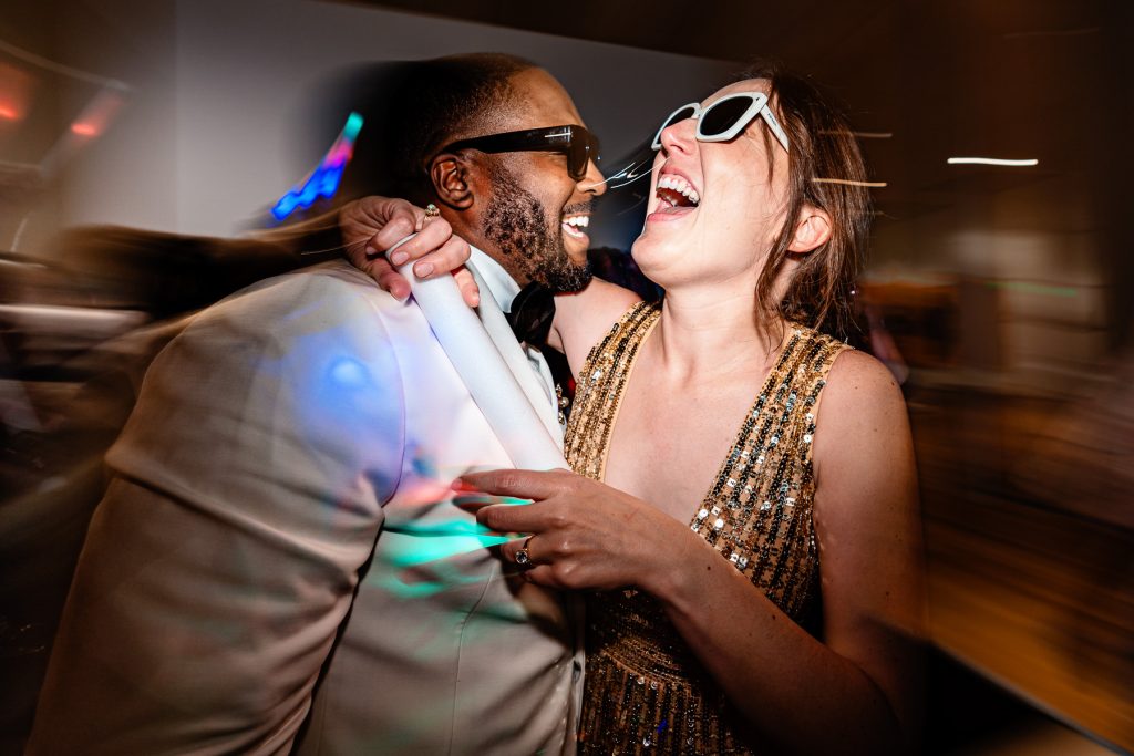 bride and groom embrace and laugh on the dance floor at their reception