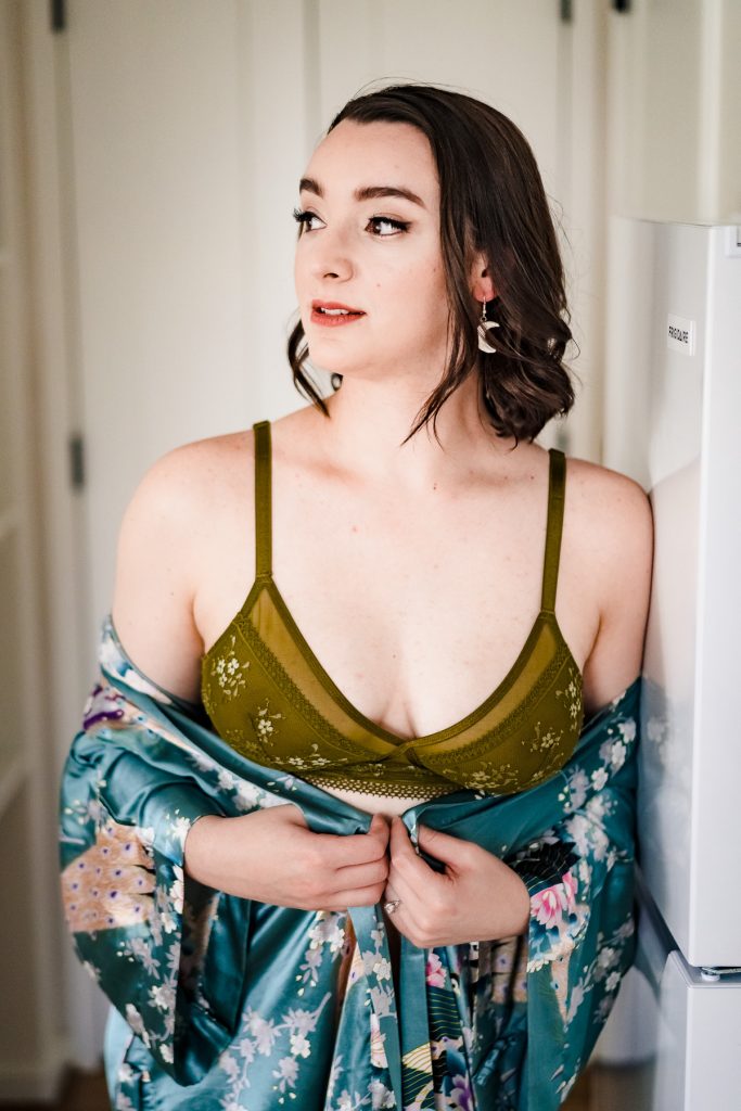 boudoir photo of a woman in a cute green bra hugging a silky floral robe around her waist | photo by Triangle Boudoir
