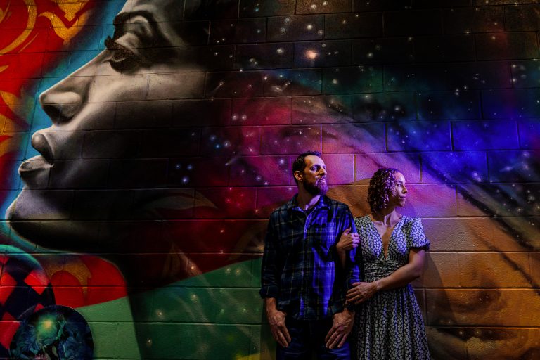 couple poses in front of a mural at Hi-Wire Brewery in Durham