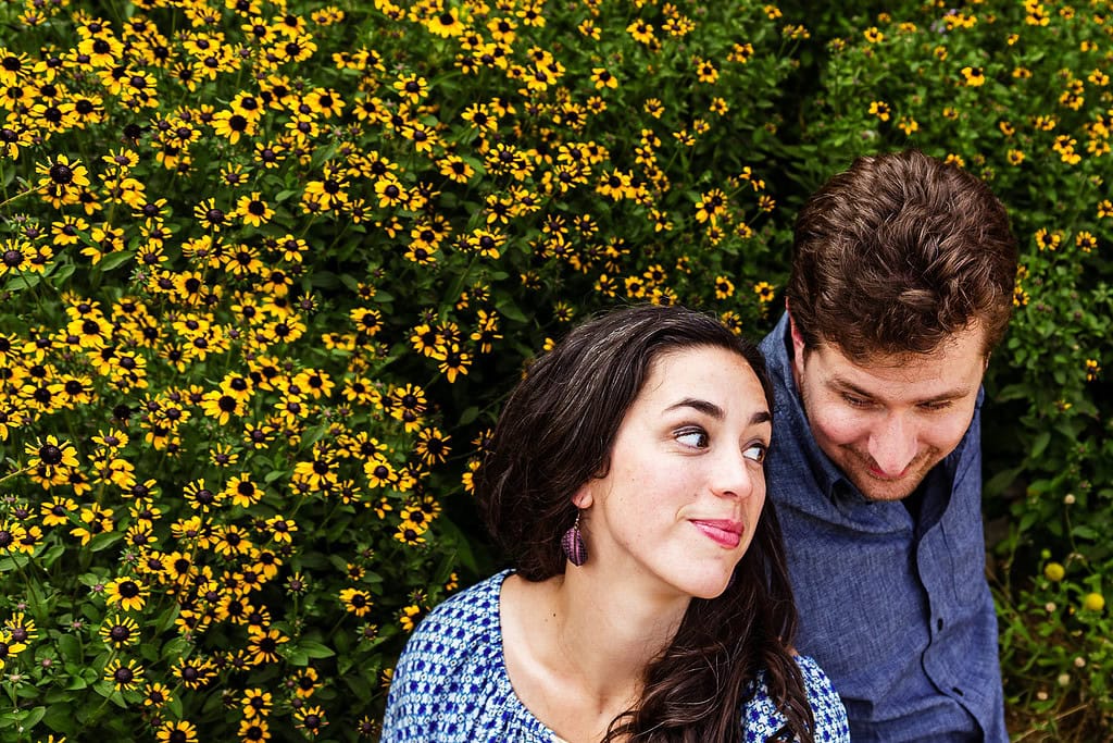 Couple sits among Black Eyed Susans at their NC Botanical garden engagement photo session