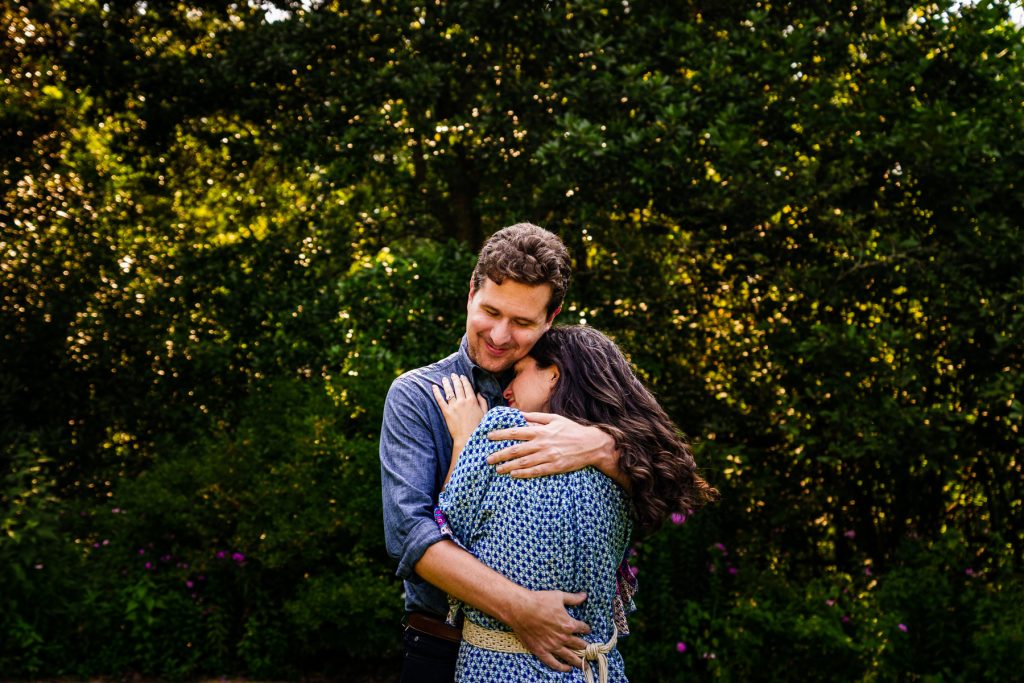 man and woman embracing with thick green foliage in the background