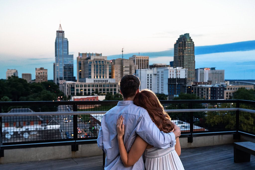 Raleigh proposal photograph of a newly engaged couple looking out at the downtown Raleigh skyline