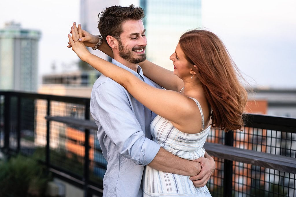 red haired woman embraces bearded man after saying yes to Raleigh proposal