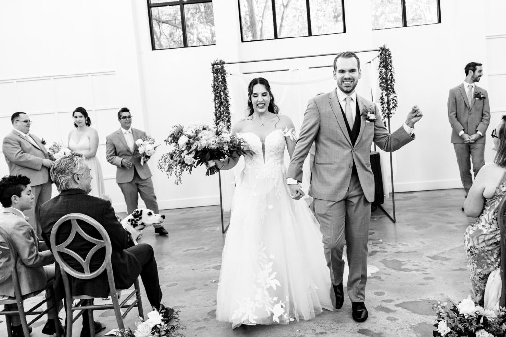 couple smiles as they recess down the aisle after their Distillery NC jewish wedding ceremony