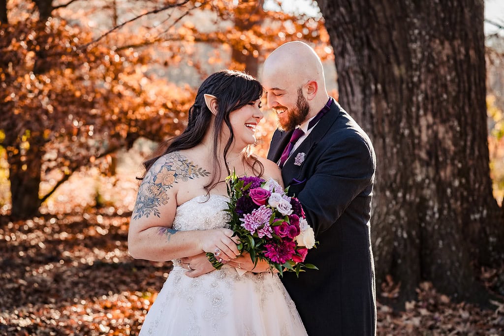portrait of a woman in a wedding dress and elf ears being embraced by a man in a vintage tuxedo for a Tolkien wedding styled shoot