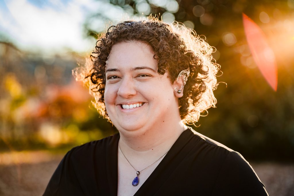 portrait of a person with short curly hair and metallic elf ears