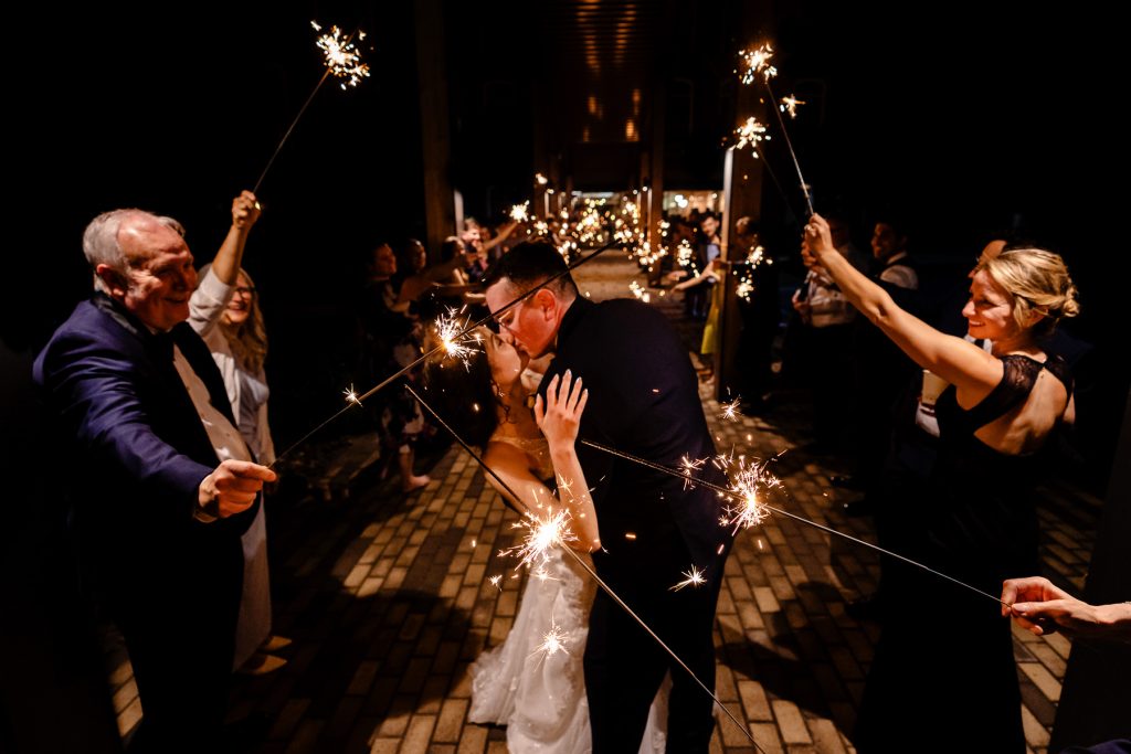groom dips and kisses bride during sparkler exit