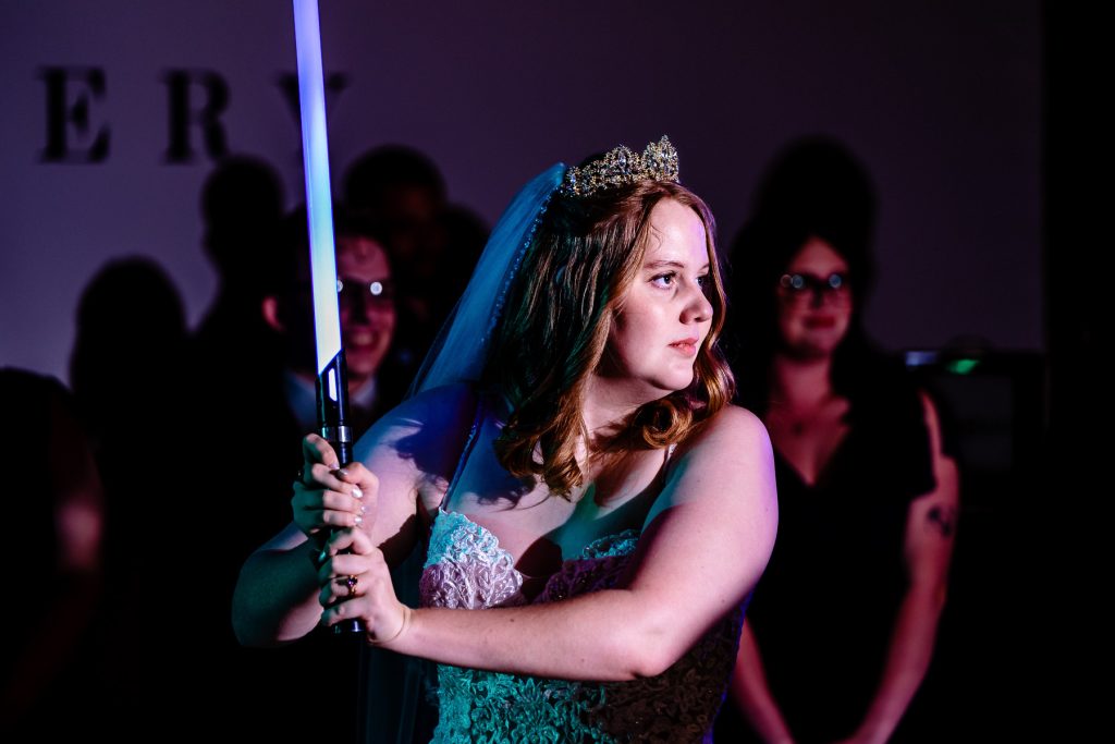 bride holds a lightsaber at her wedding reception