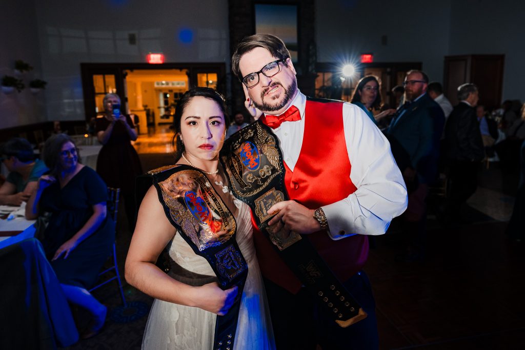 bride and groom pose with wrestling championship belts at their wedding reception | photo by Kivus & Camera
