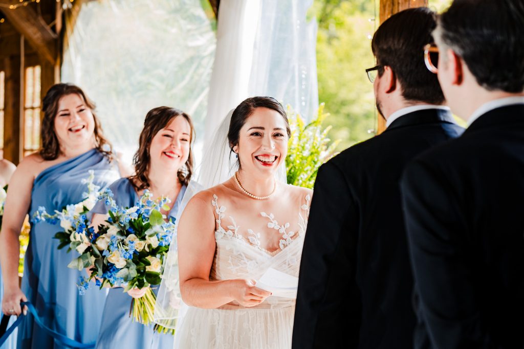 bride smiles while reading her vows during a wedding ceremony at Chapel Hill Carriage House | photo by Kivus & Camera