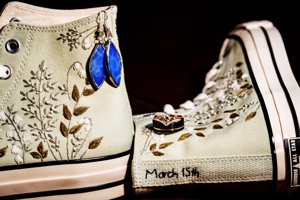 detail photo of embroidered converse sandals, with wedding rings and bride's wedding jewelry