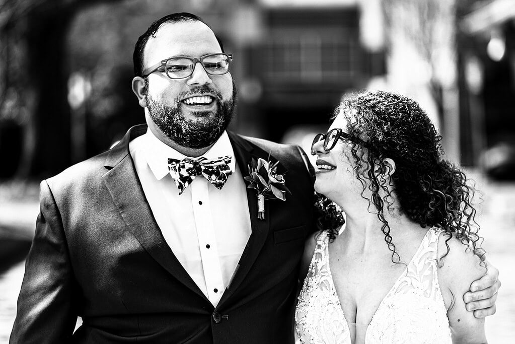 black and white photograph of a couple in wedding attire smiling and laughing