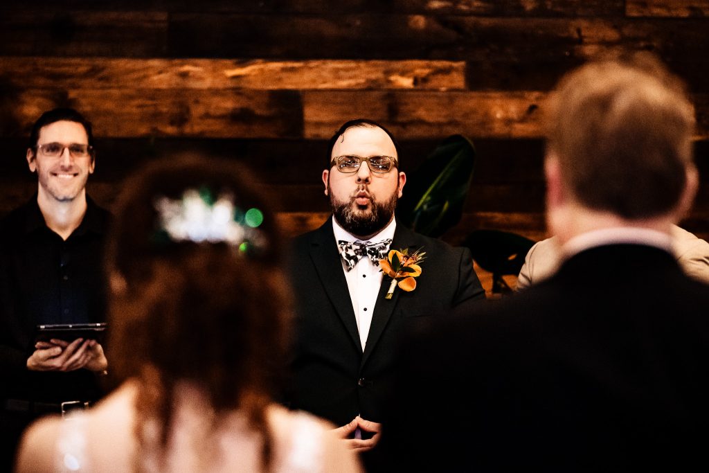 photo of a groom's reaction taken from behind the bride and her father