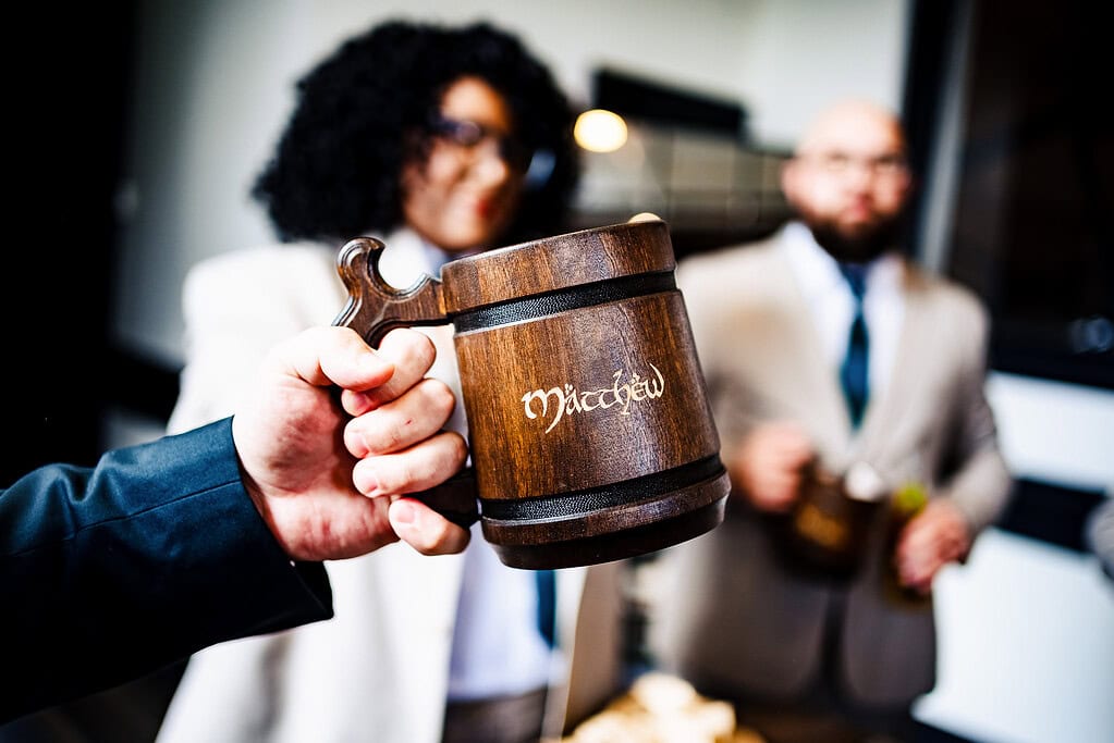groom toasts with a custom beer stein, as his friends circle around