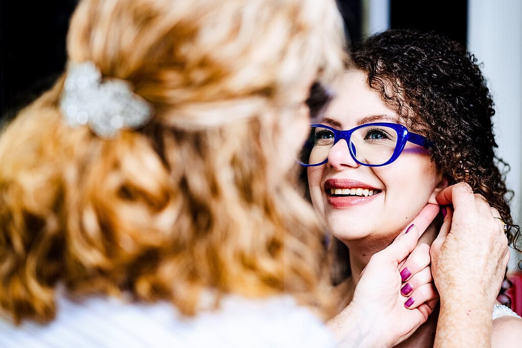 mother of the bride helps bride put her earrings on