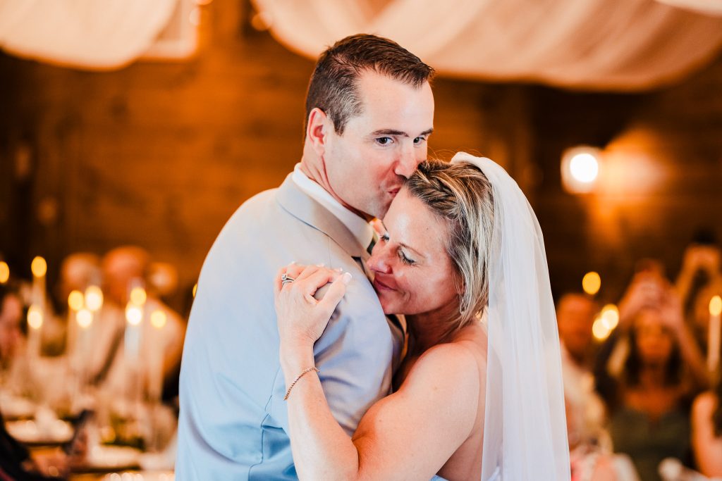 groom kisses bride on the temple during their first dance