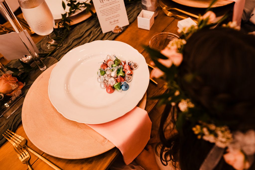 flower girl has a plate full of hershey's kisses at a wedding reception