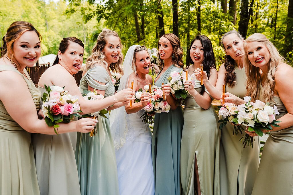 bride and bridesmaids make silly faces for the camera while holding test tube tequila shots