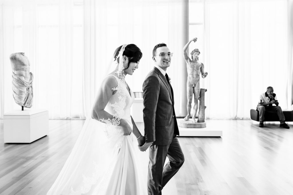 couple in wedding attire walks hand in hand through the NC Museum of Art | photo by Kivus & Camera