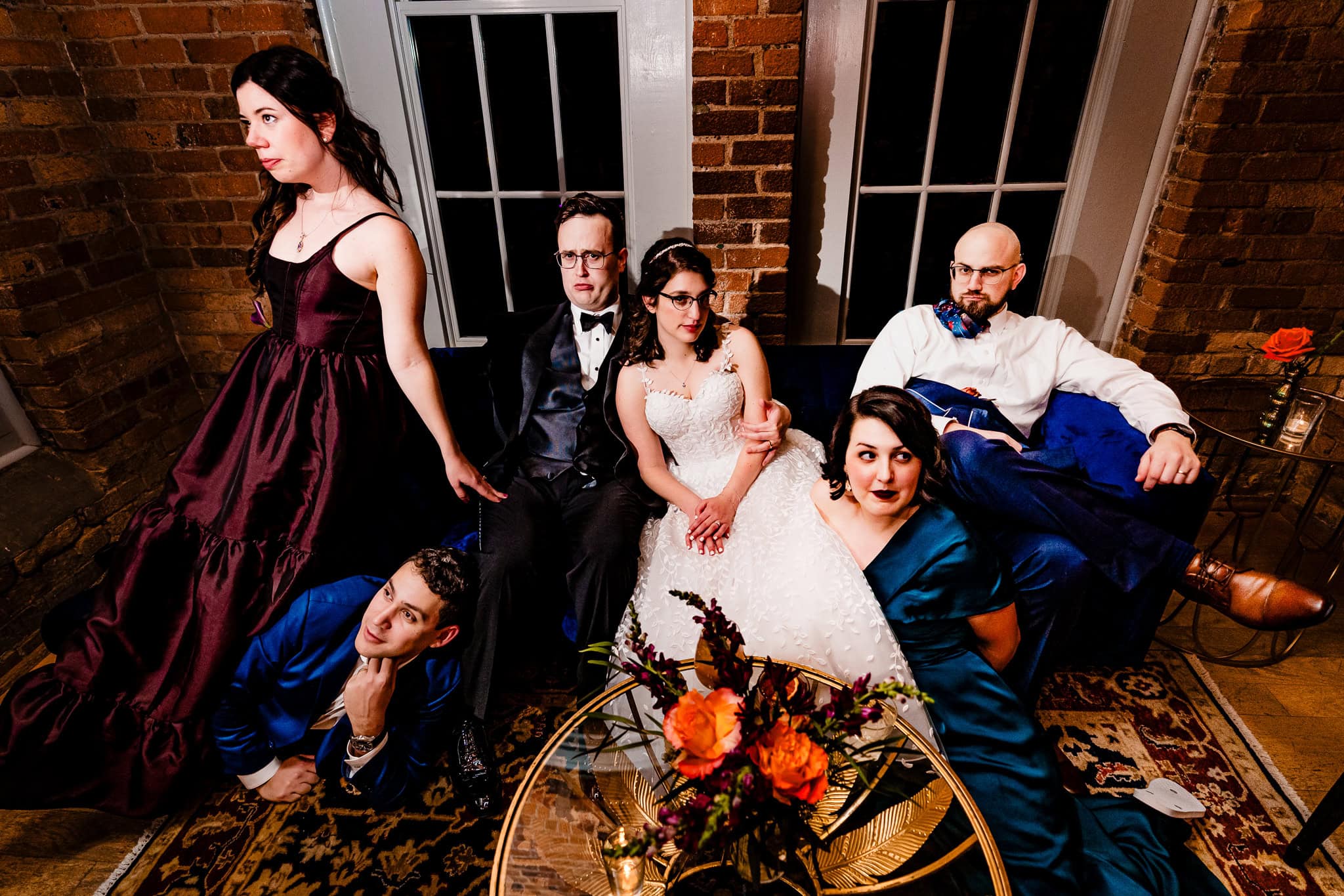 bride and groom pose with their wedding party in a lounge at the end of the reception | photo by Kivus & Camera